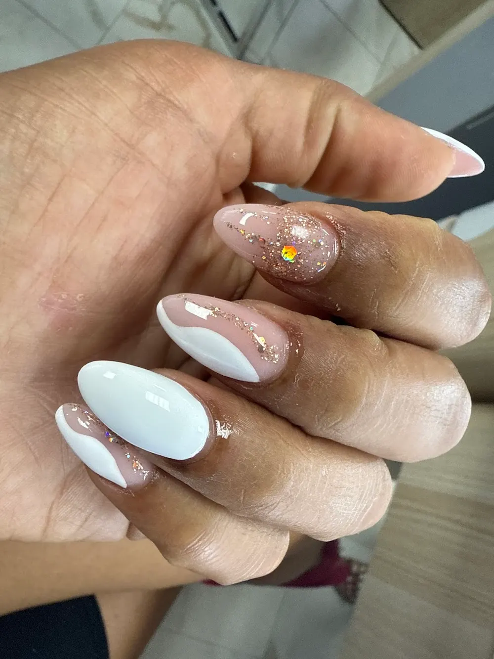 Nude and white almond nails with rose gold glitter accents, styled by Beauty Nails Spa in Champaign