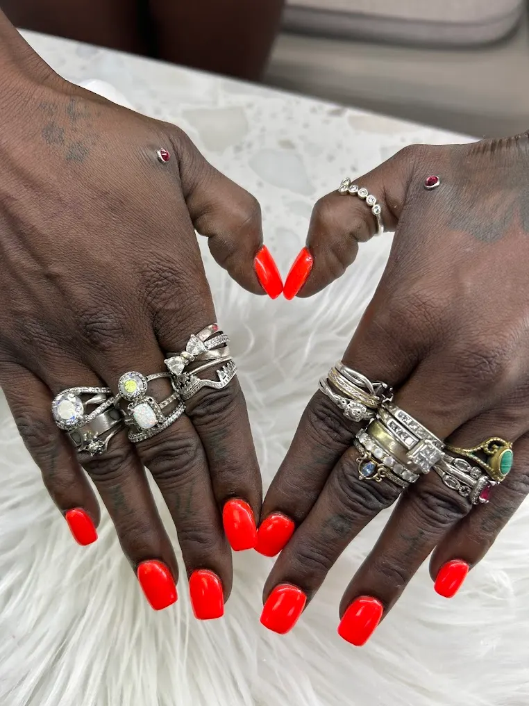 Red and orange tip nails styled with statement rings